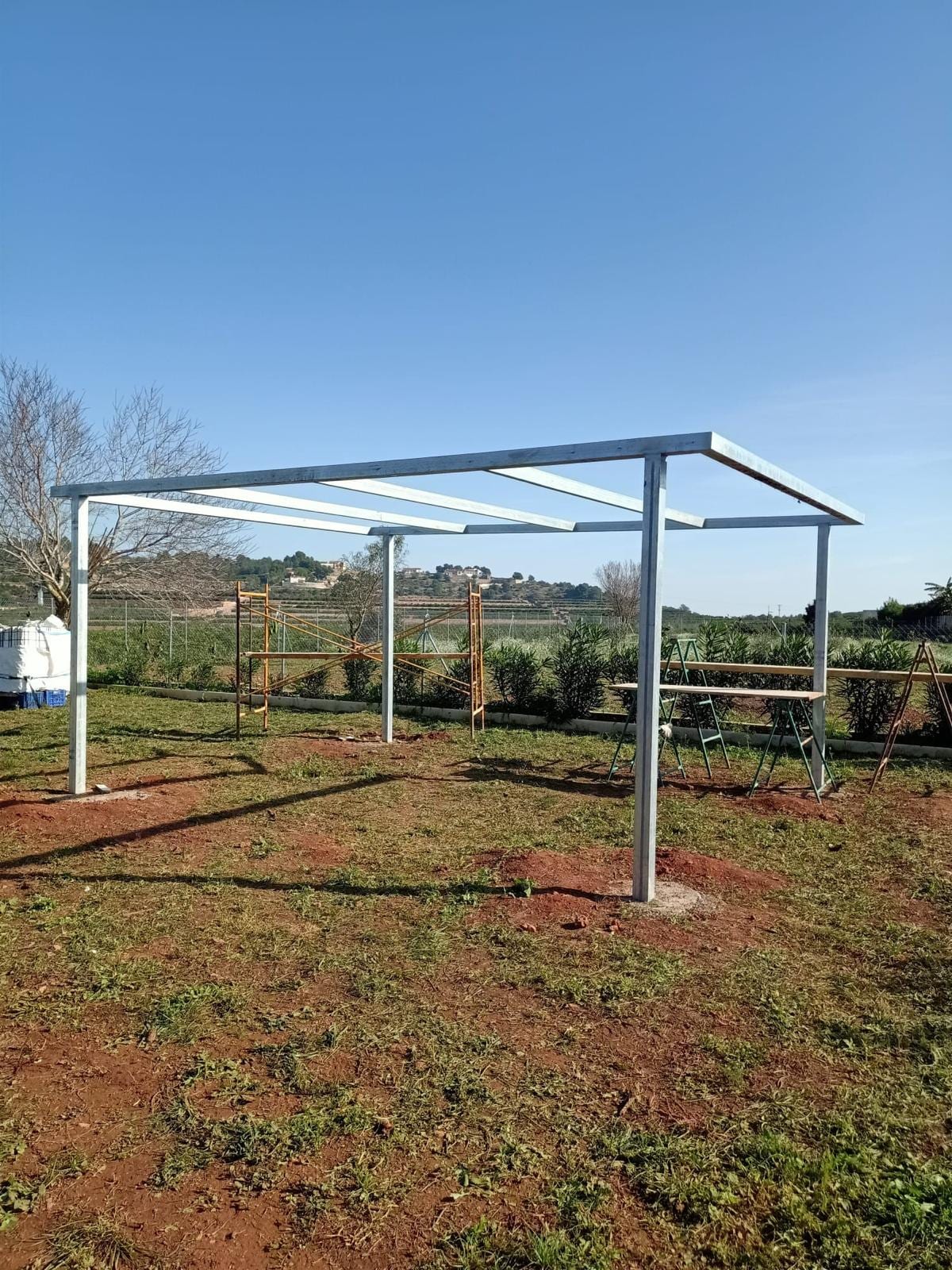 estructura de pérgola galvanizada montada en una parcela con cielo azul