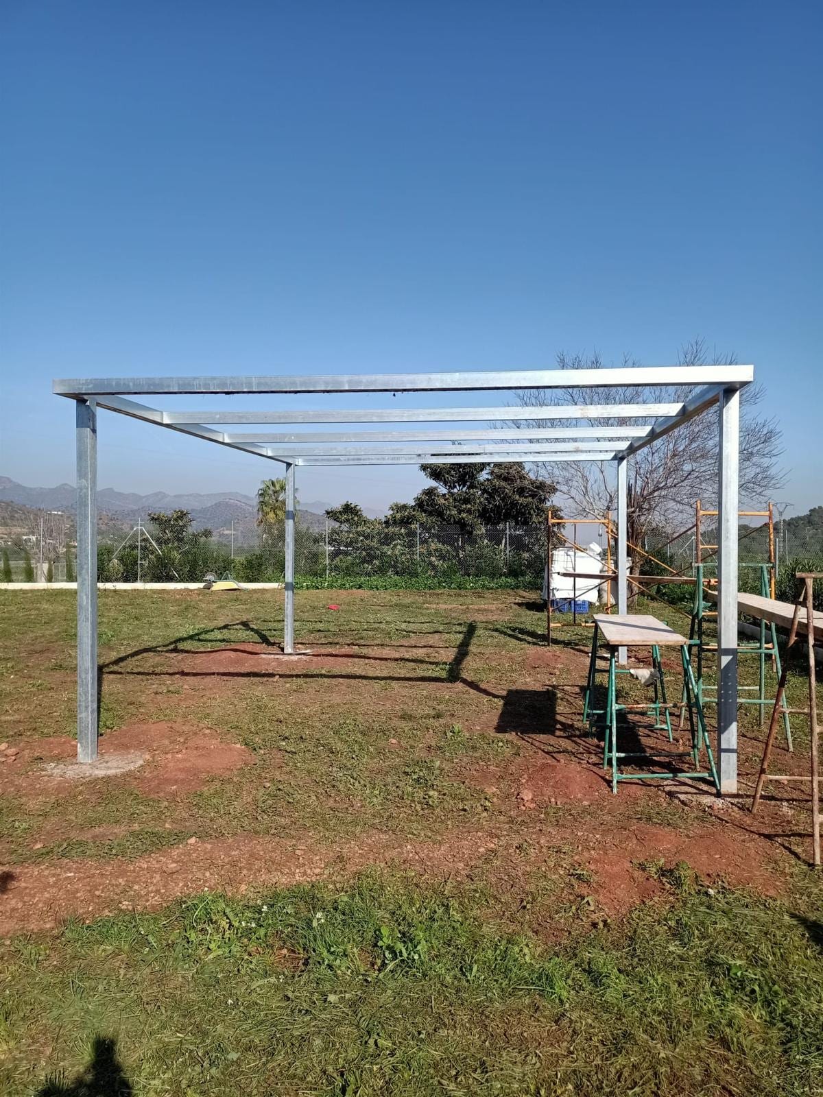 estructura de pérgola galvanizada vista de frente, con montañas al fondo