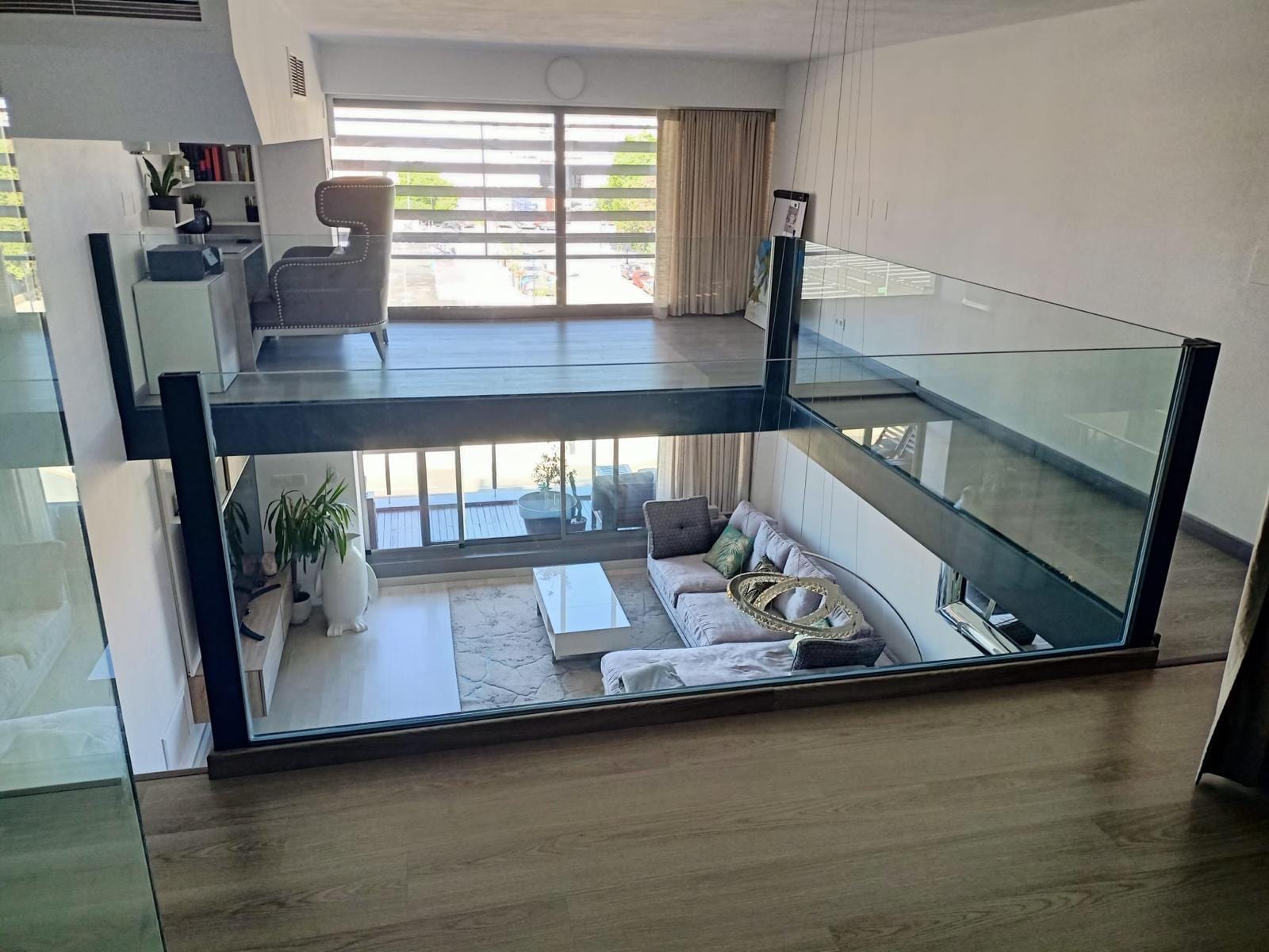 altillo con estructura negra y antepecho de vidrio sobre un salón a doble altura