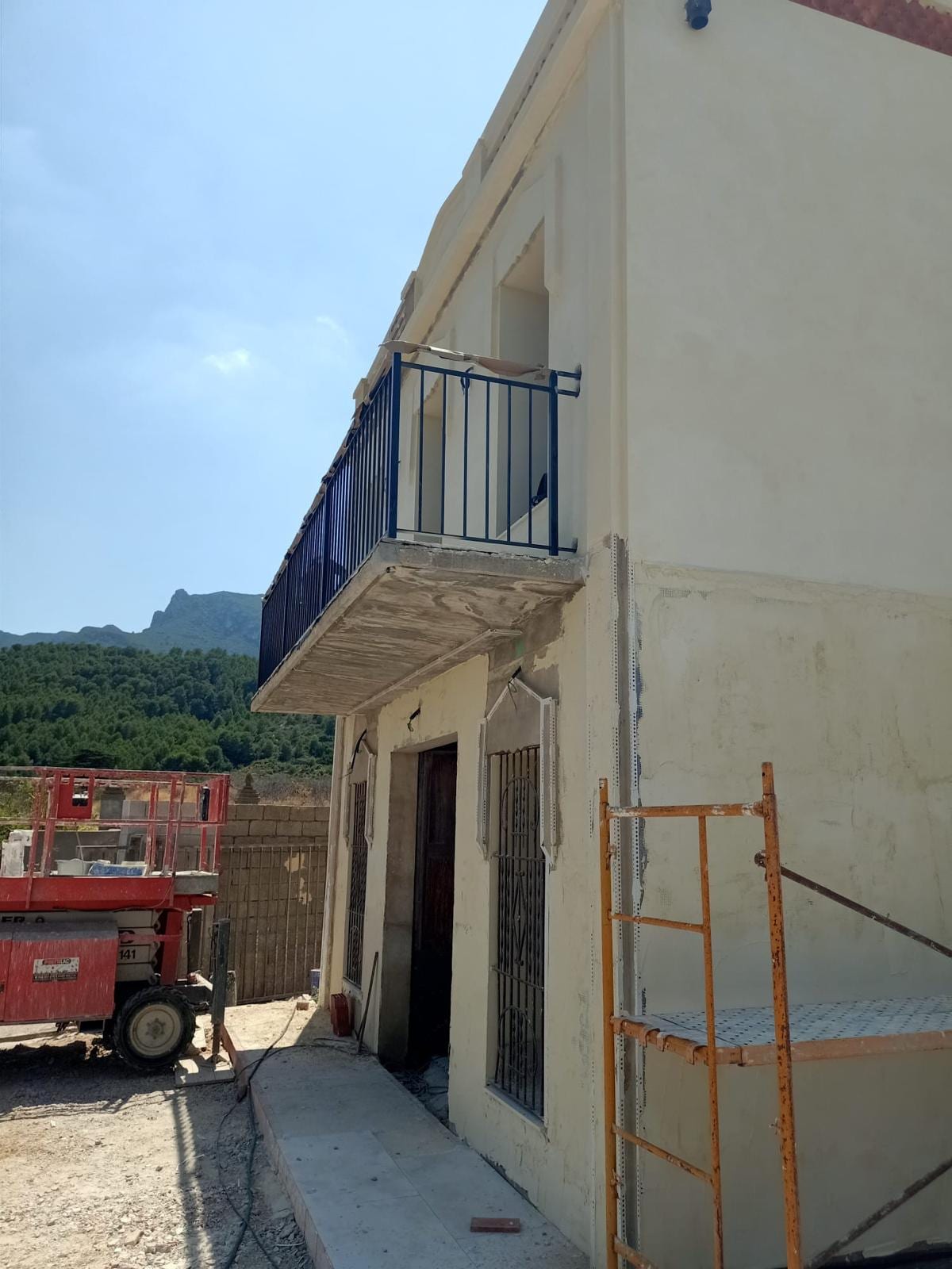 balcón con barandilla azul oscuro instalada en fachada en obra